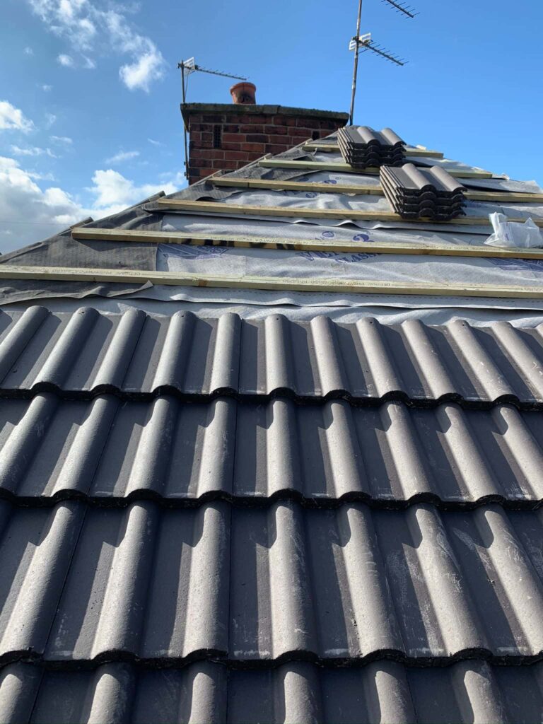 This is a photo of a hipped re-roof which is part re-tiled, work is in progress by Northampton Roofing Services